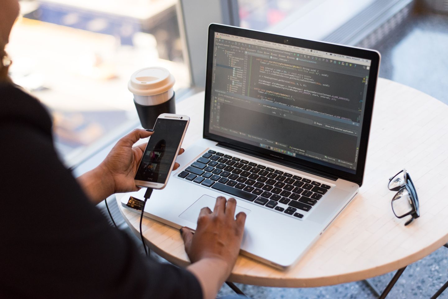 A developer working with a phone and laptop
